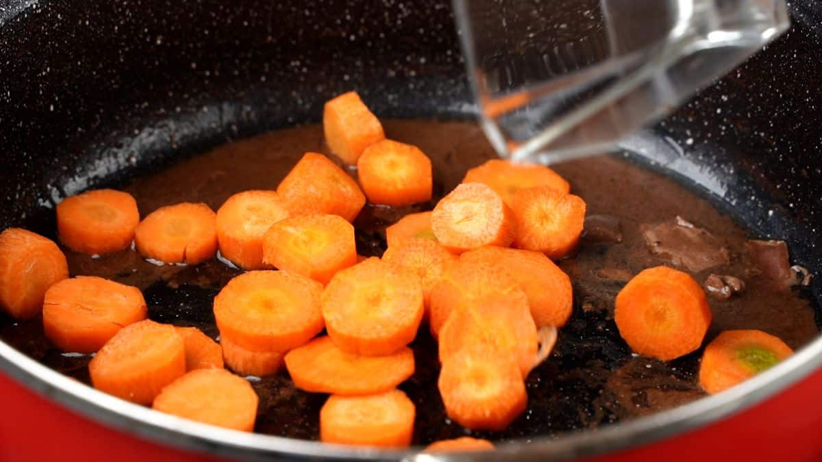 carrots being added to stew pot