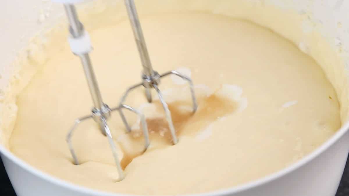 mixer in white bowl of cheesecake batter