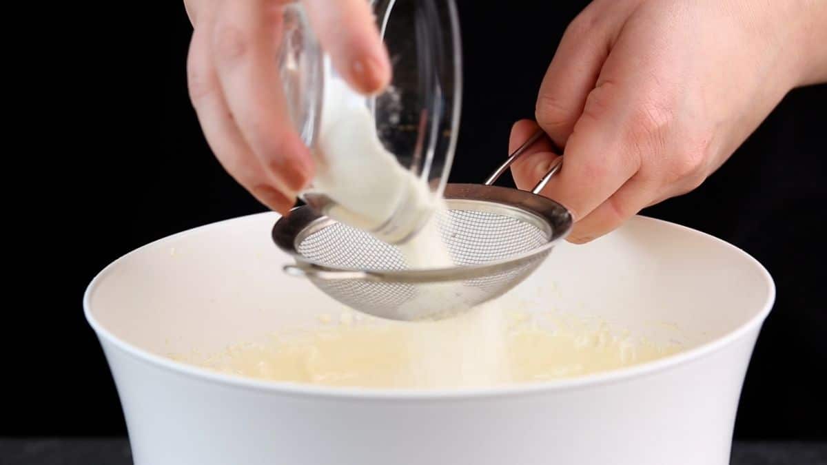 flour being sifted into cheesecake batter