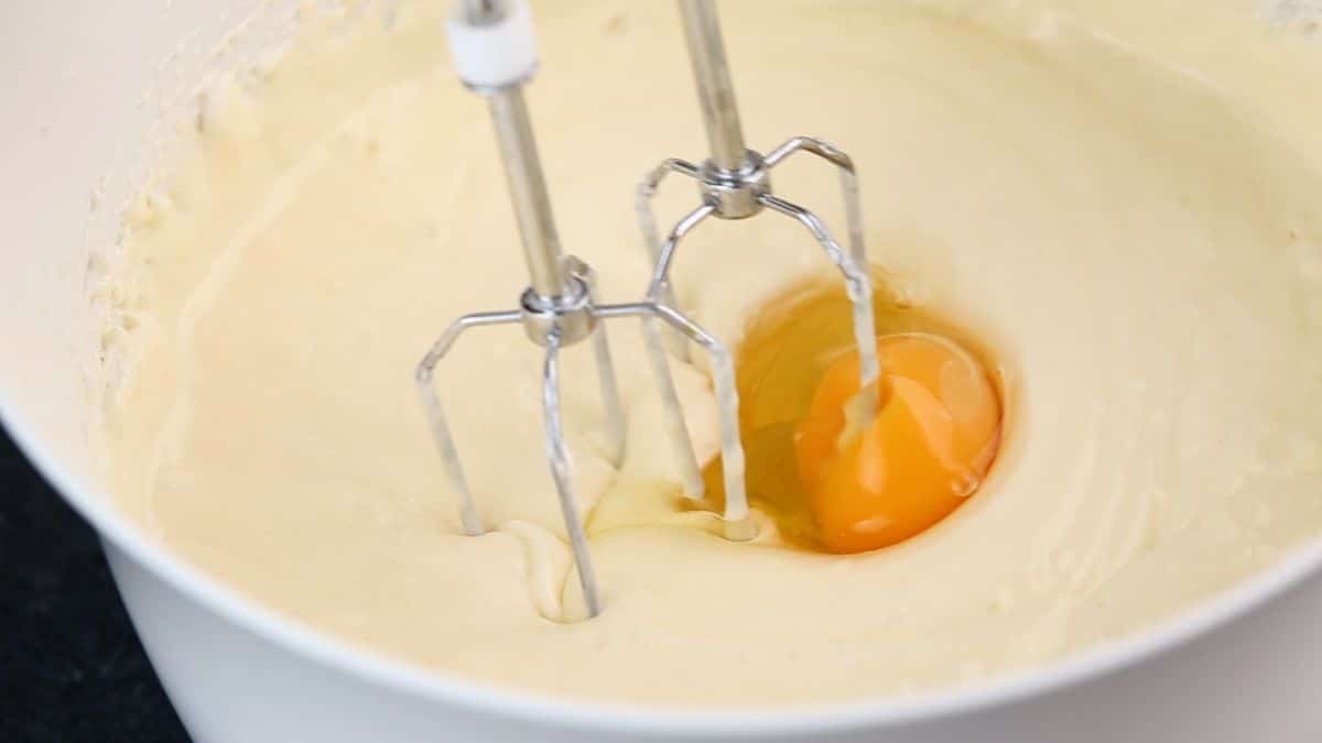 egg in bowl with cream cheese and hand mixer