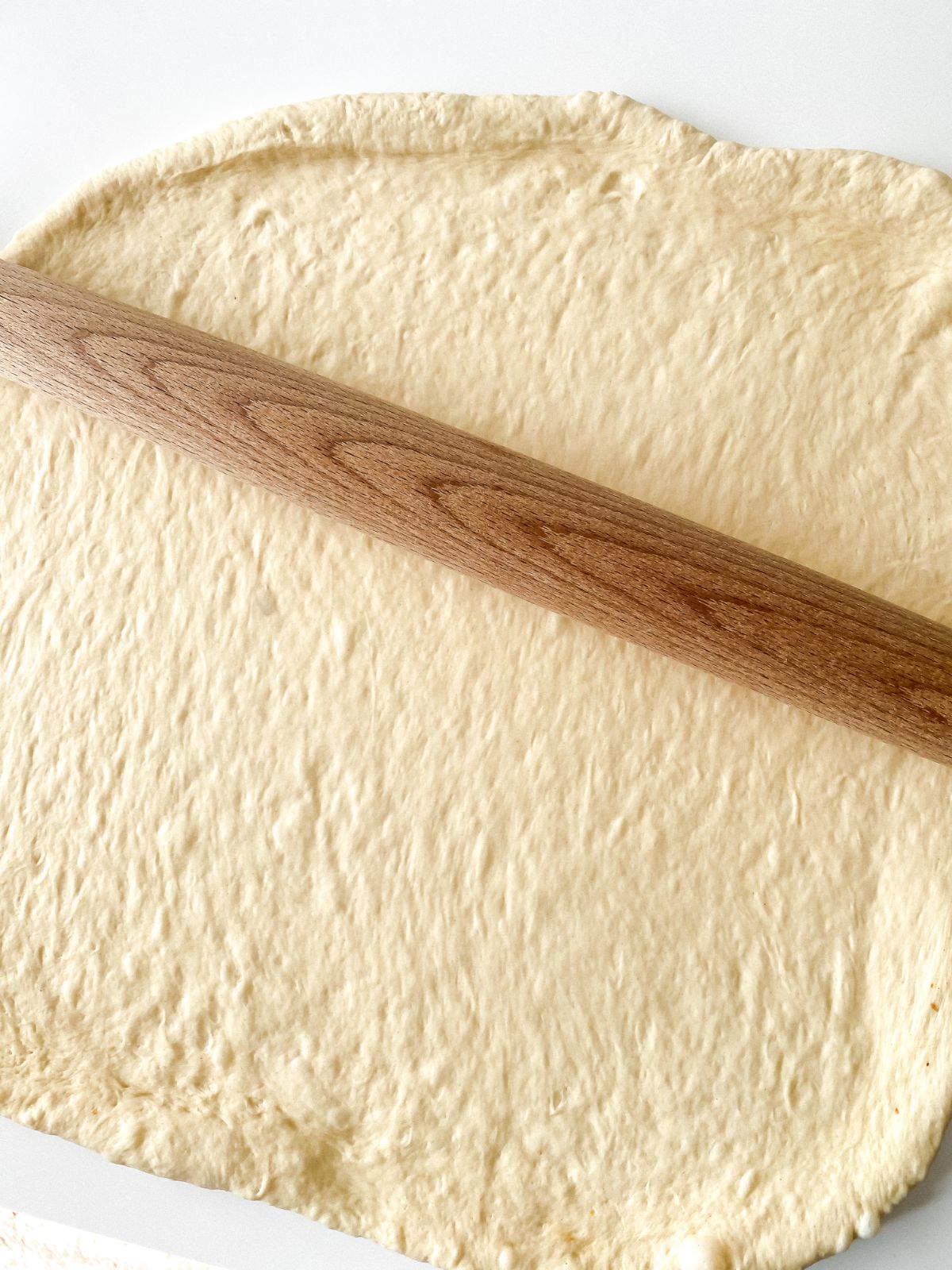 rolling pizza dough with wooden pin