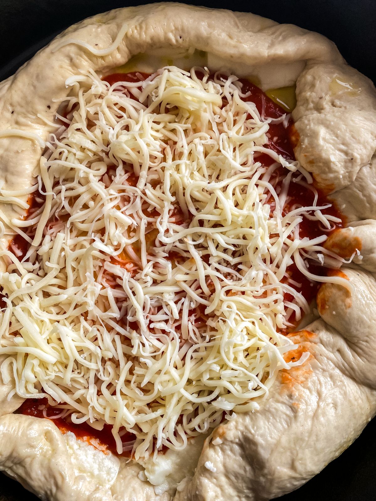cheese on top of pizza dough in skillet