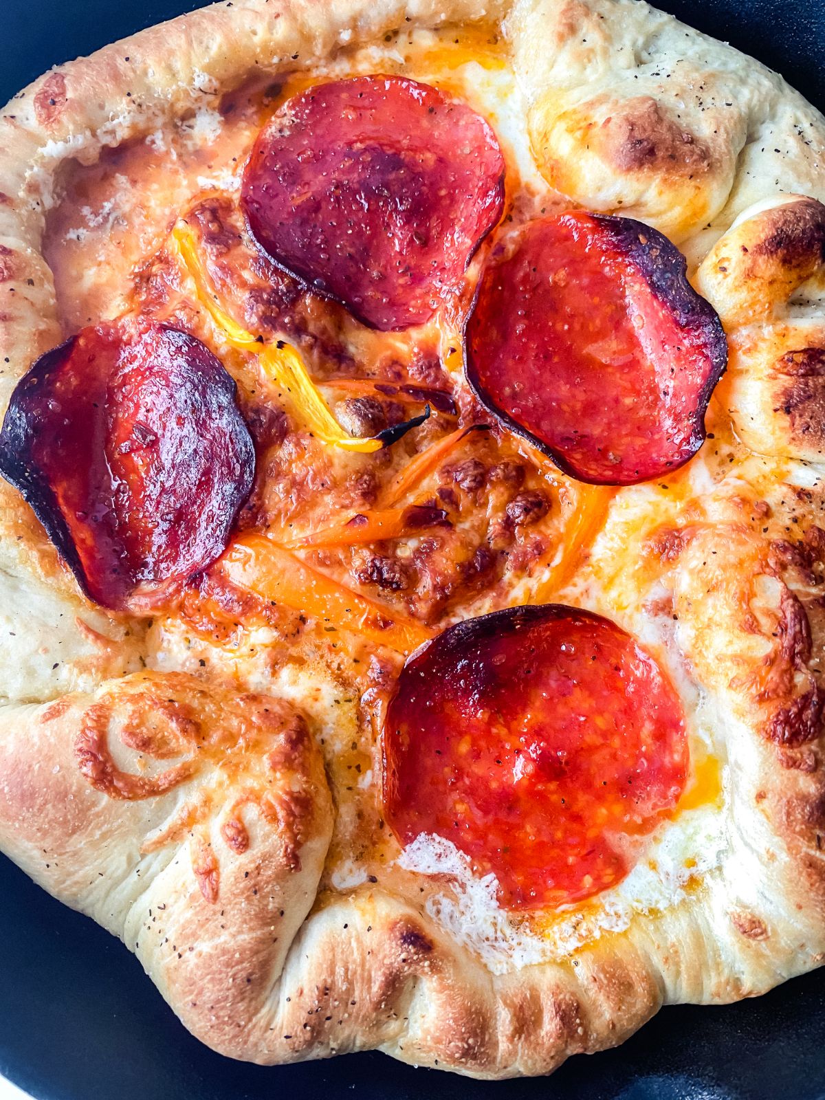 pepperoni and peppers on top of pizza in skillet