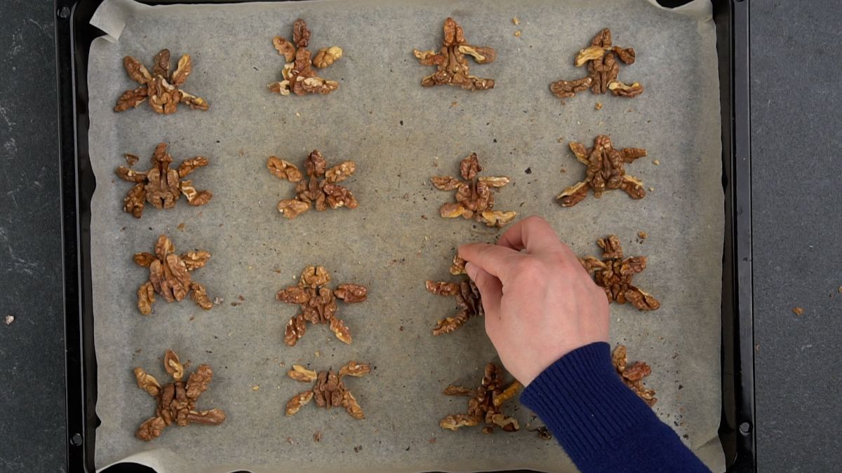 walnuts in turtle shapes on parchment lined baking sheet