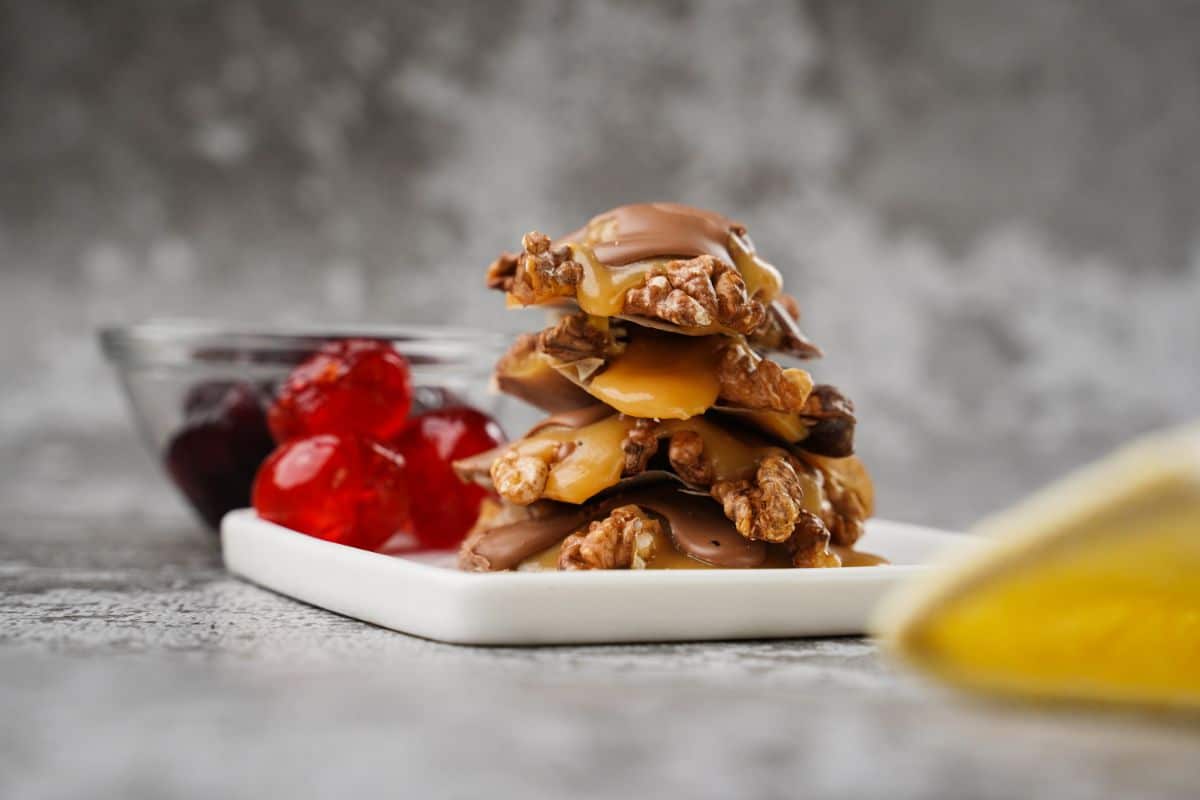 stack of turtle candy on white plate with cherries