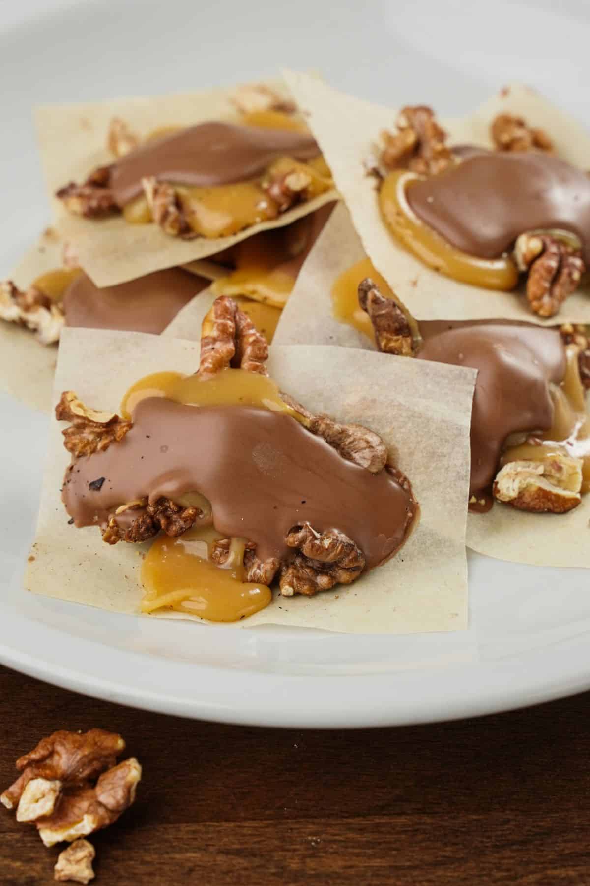 individual turtle candies on parchment paper on white plate