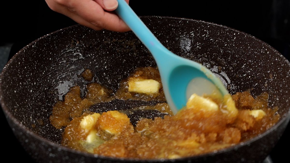 caramel mixture in skillet being stirred by teal spoon