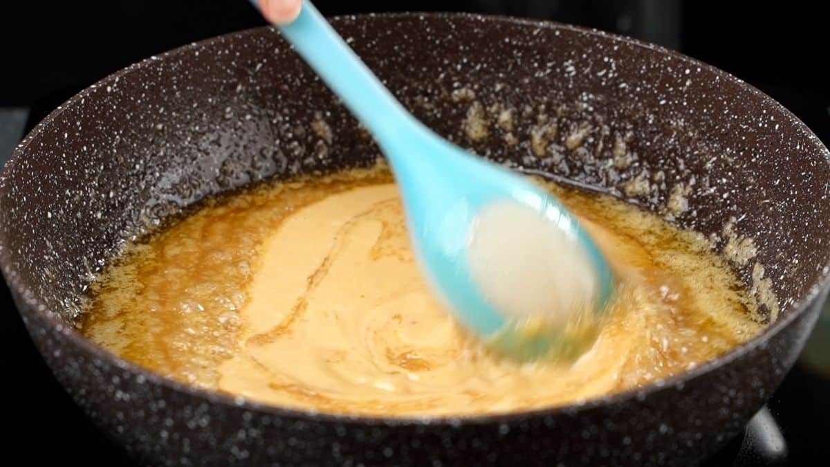 blue spoon stirring caramel in skillet