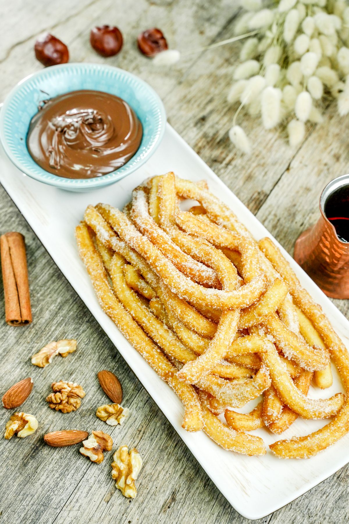 white rectangle plate holding churros and teal bowl of caramel sauce
