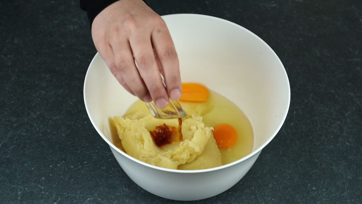 eggs and vanilla being added to bowl of dough
