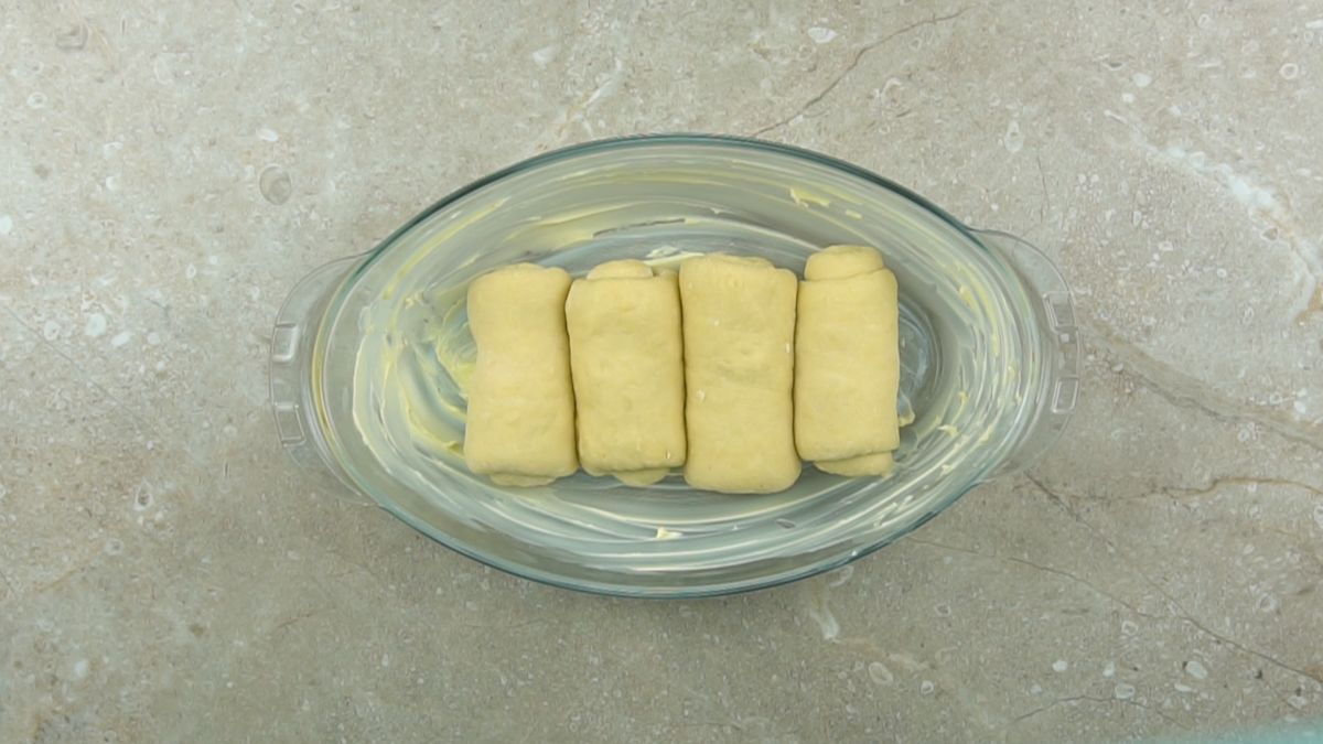 four rolls of dough in glass oval baking dish