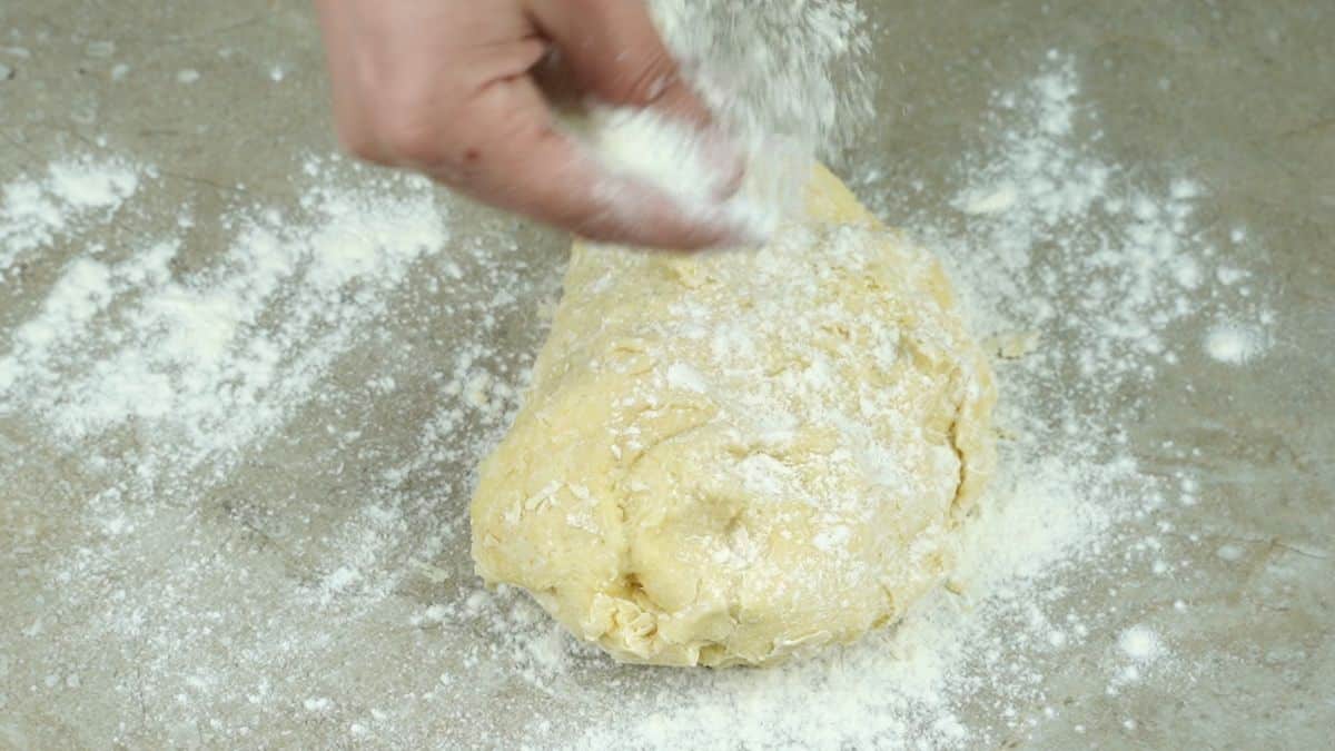 flour being sprinkled over the top of dough