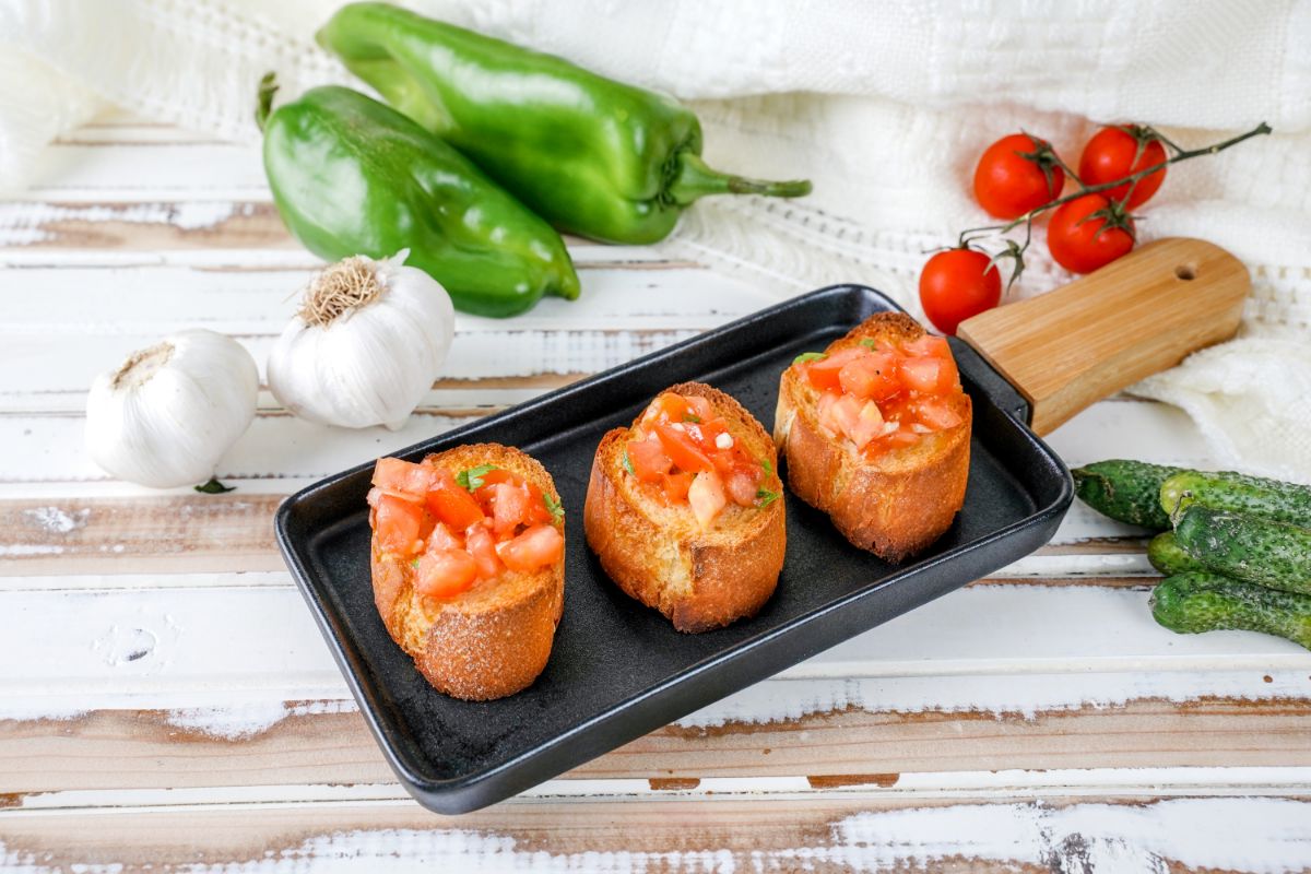 baguette with tomato bruschetta on top sitting on black plate