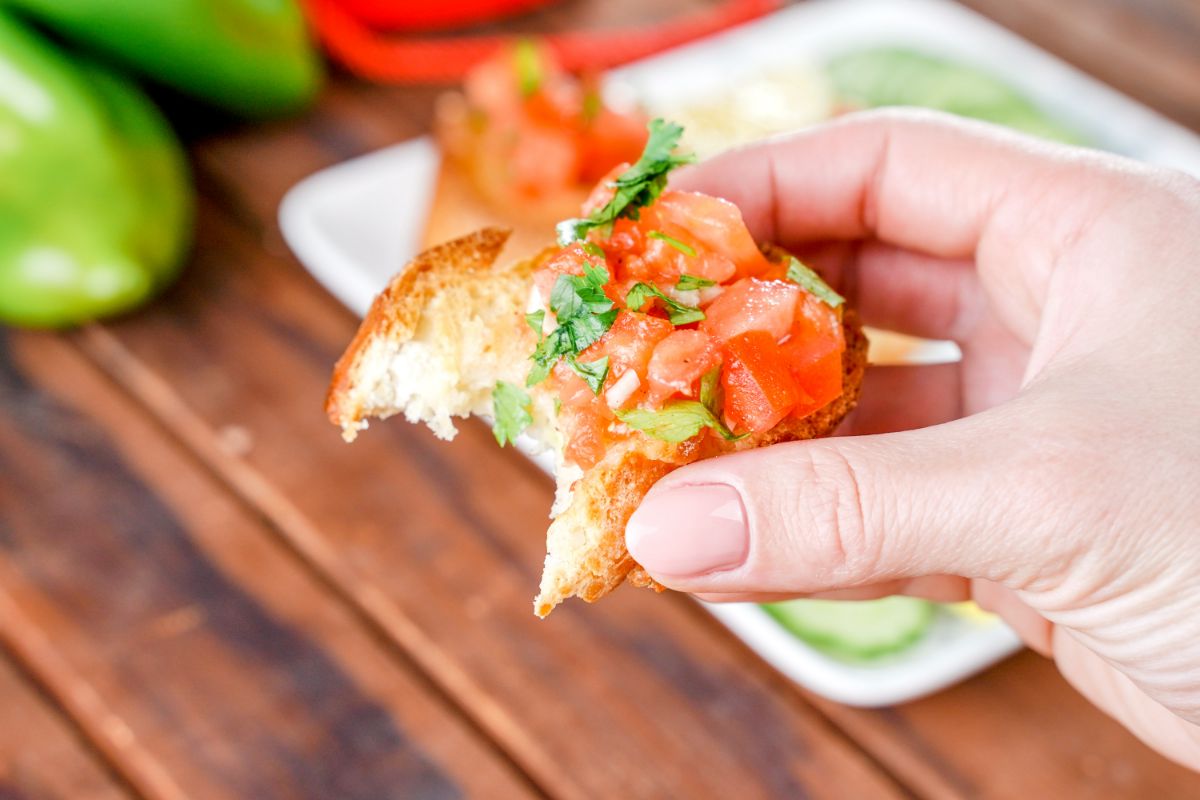 hand holding bruschetta with bite out of it