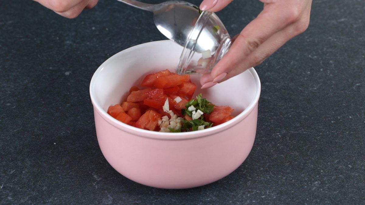 garlic being added to pink bowl of tomato