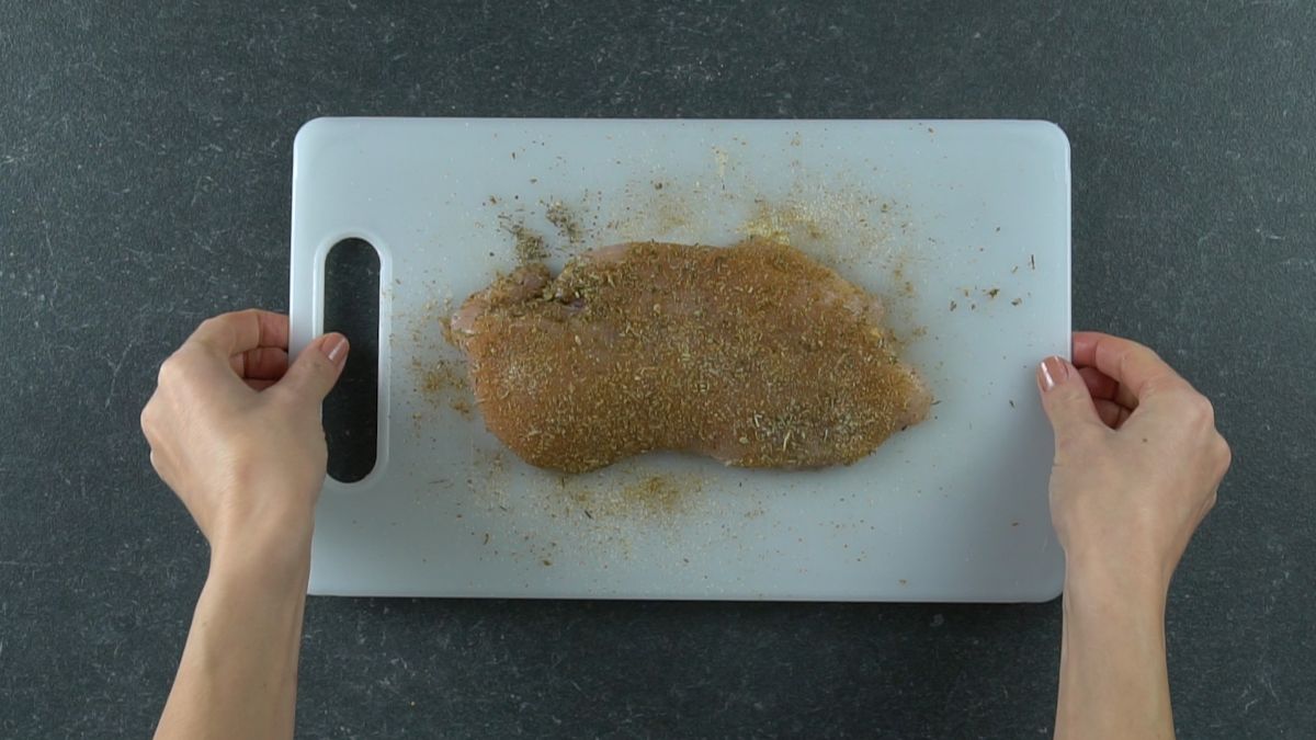seasoned chicken breast on white cutting board