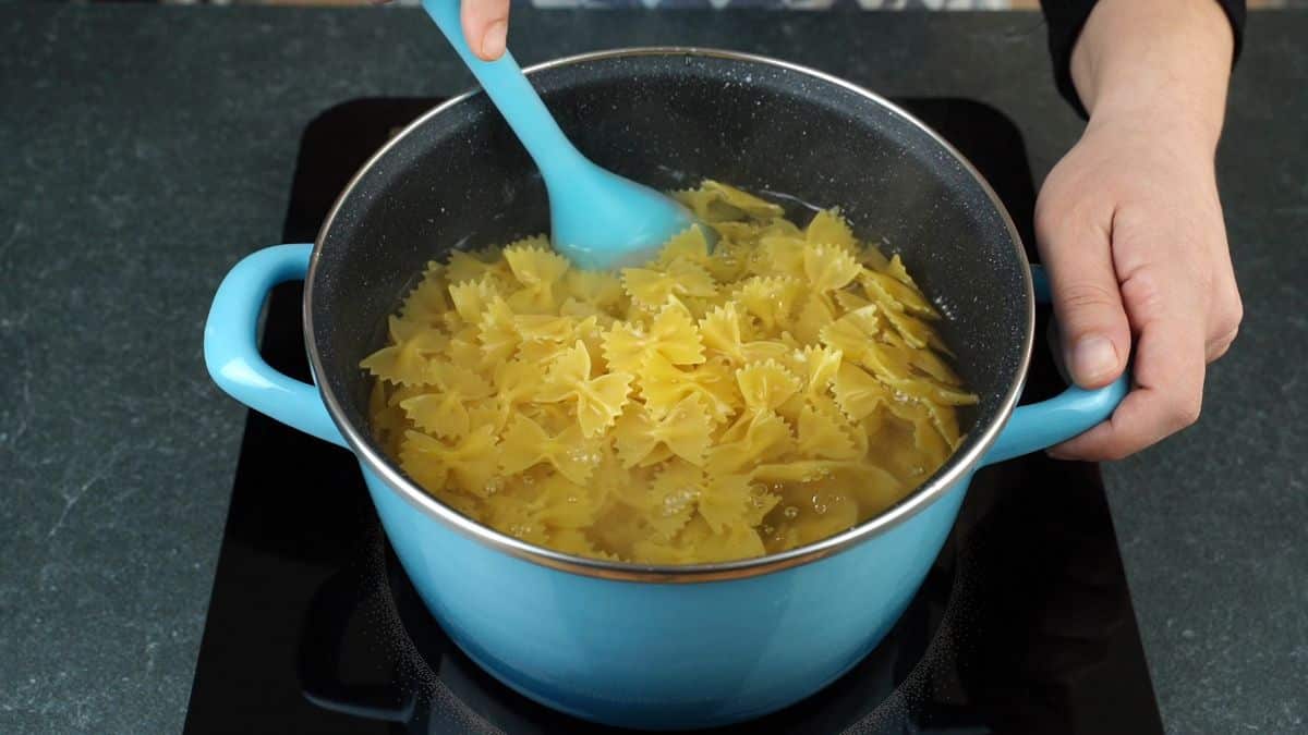 pasta being cooked in large blue stockpot