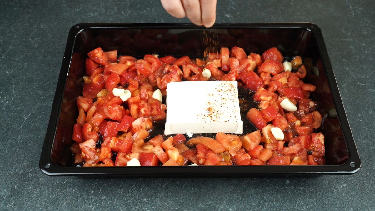 adding spices to top of feta in baking sheet