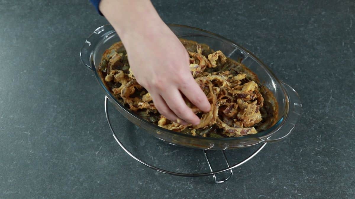 crunchy onions being put on top of green bean casserole
