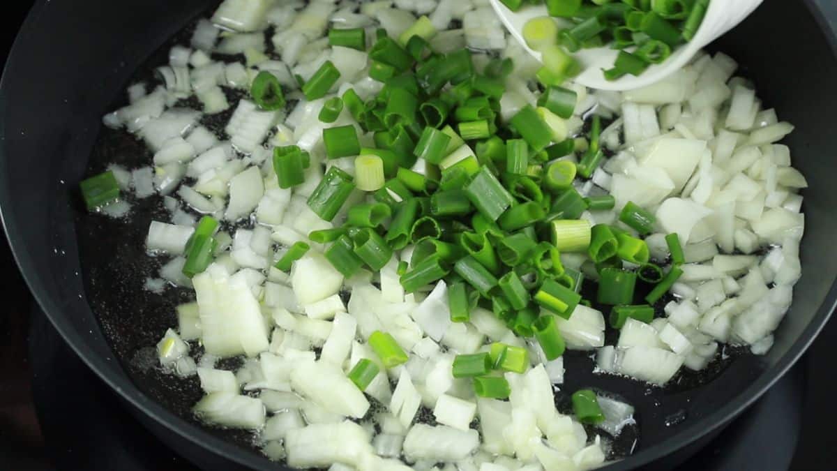 white and green onion pieces in skillet