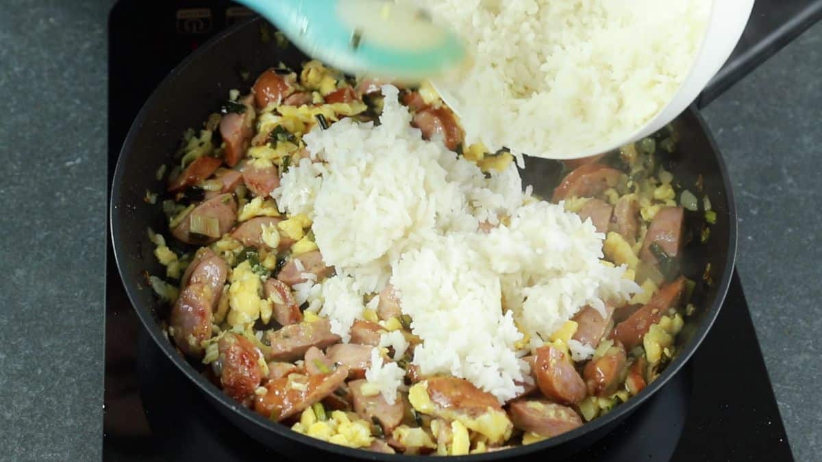 cooked white rice being added to skillet