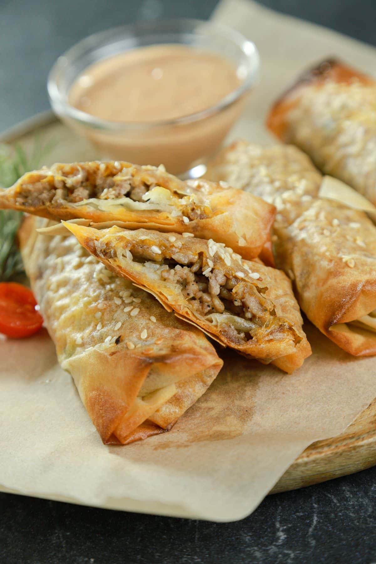 big mac eggroll cut in half sitting on parchment paper with other eggrolls