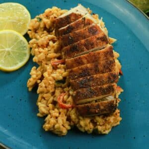 cajun chicken over bed of orzo on teal plate