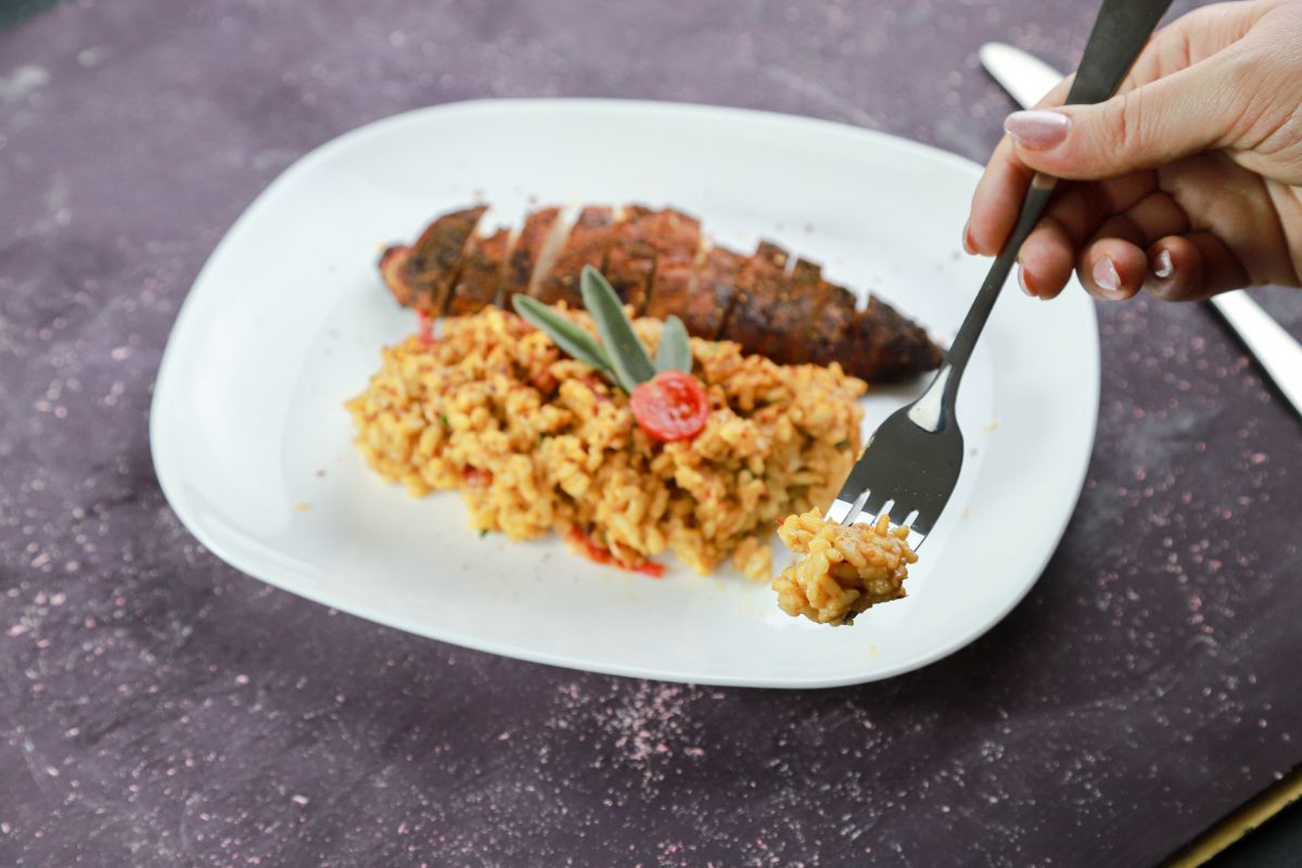 hand holding fork of orzo above white plate