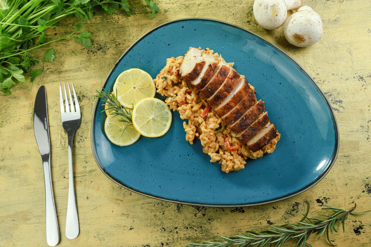 Cajun chicken and orzo on teal plate on top of light yellow table