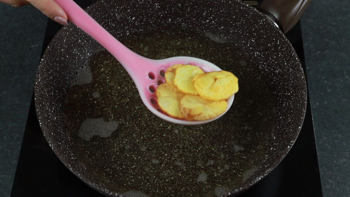 pink spoon lifting fries out of oil