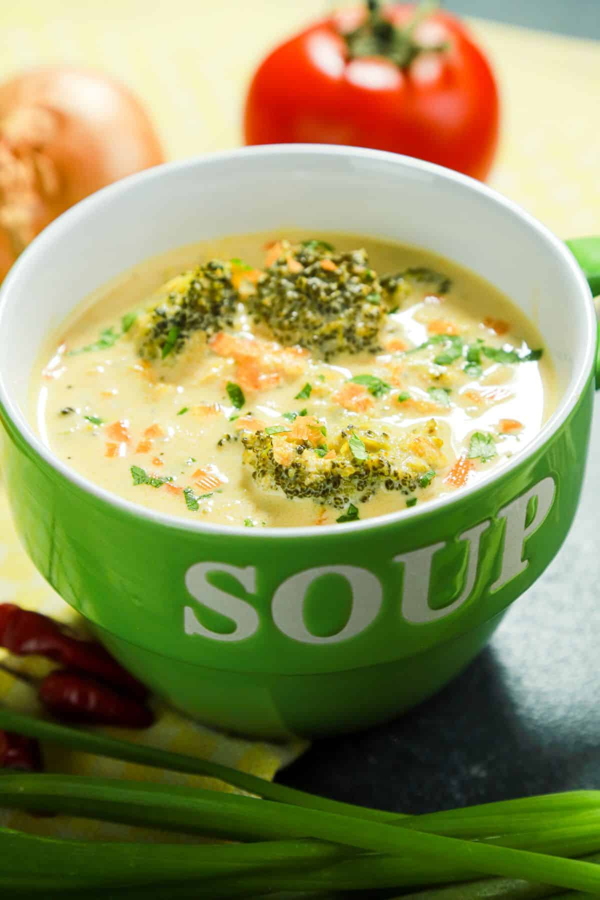 green bowl that says soup in white filled with broccoli soup