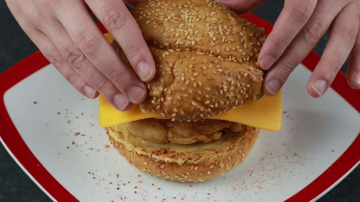 hands assembling chicken sandwich
