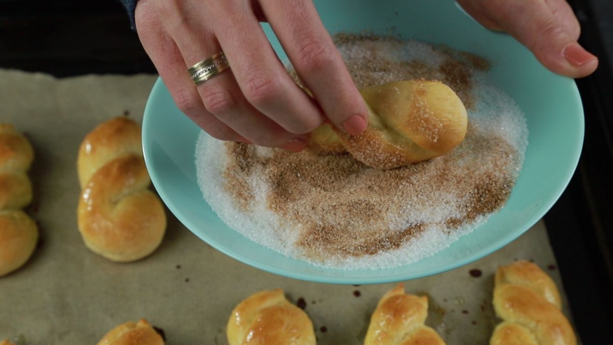 hand rolling donut through cinnamon sugar