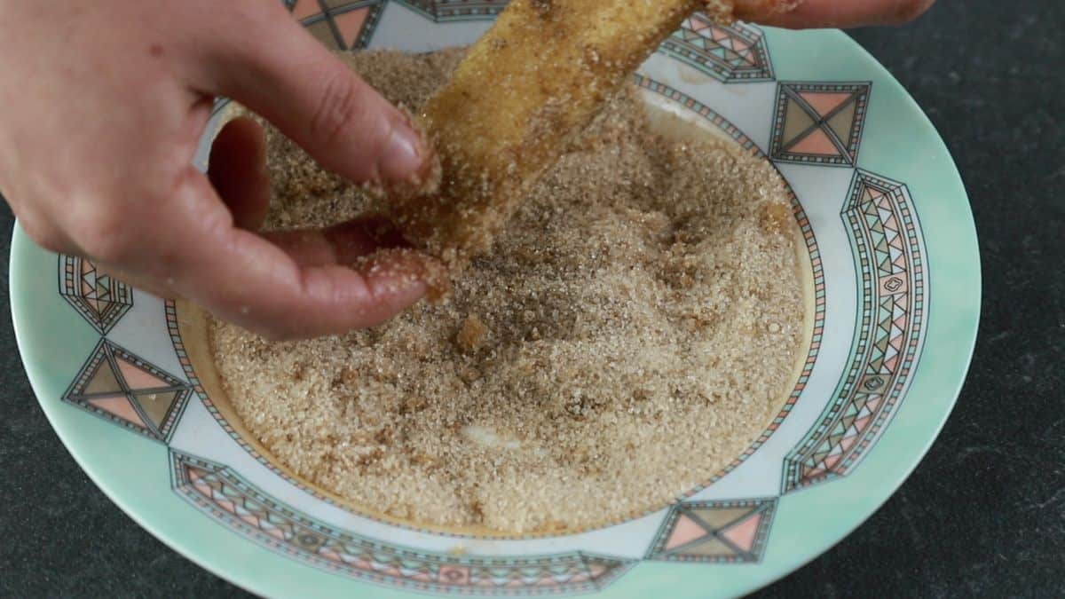 bread being dipped into bowl of cinnamon sugar