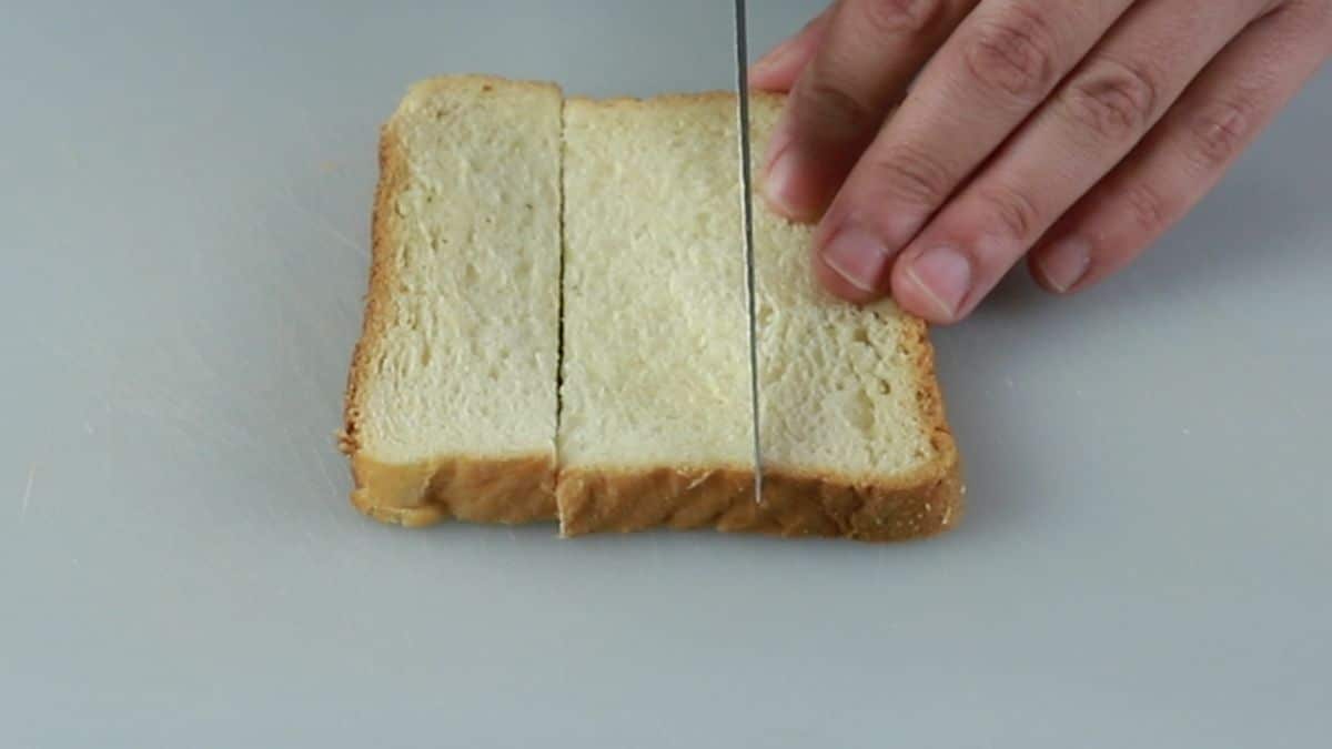 slice of white bread sliced into three pieces on white cutting board