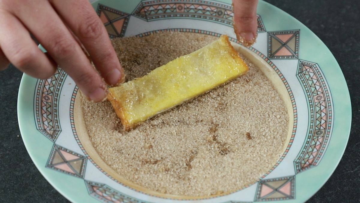 bread strip being rolled in sugar and cinnamon