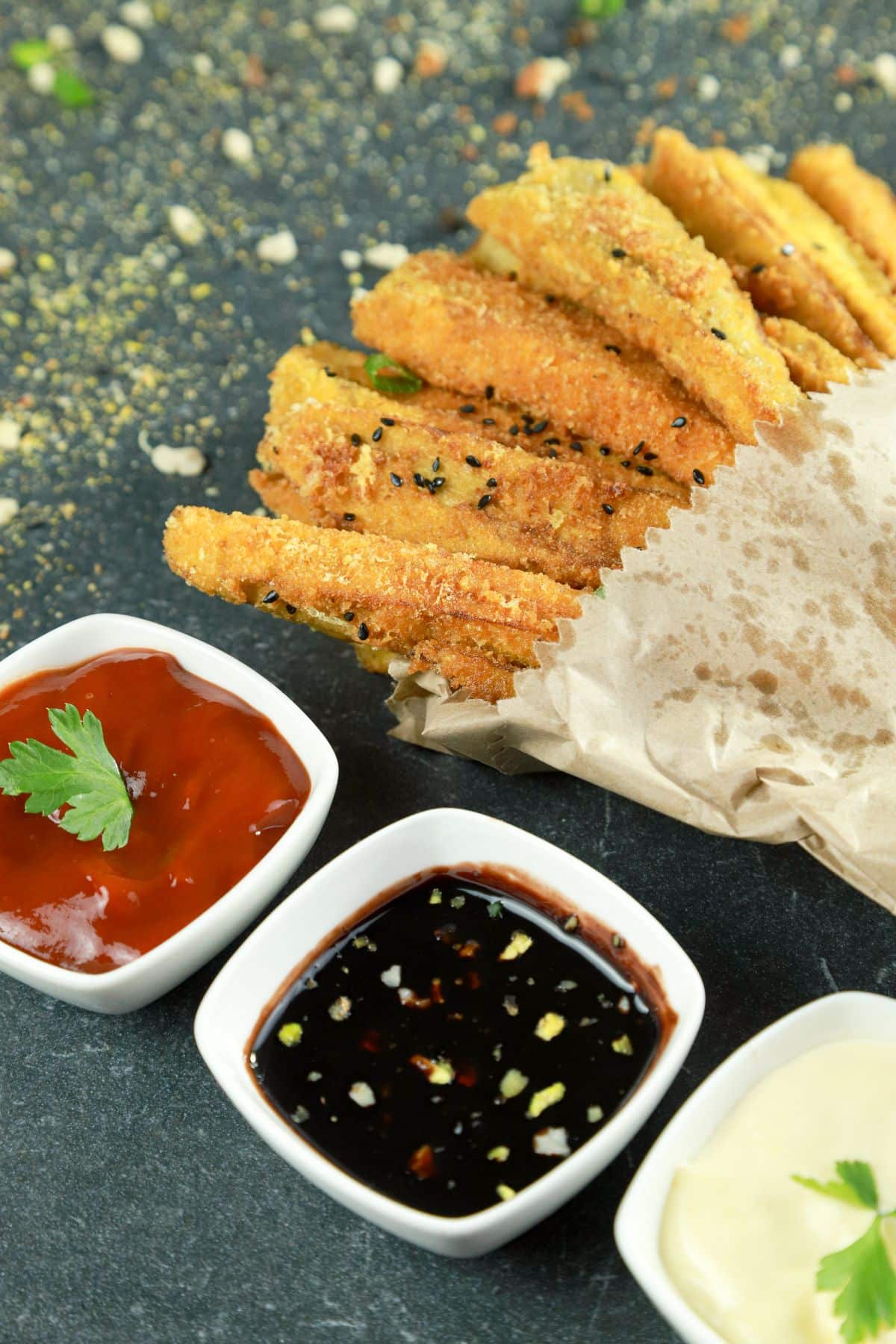 eggplant fries in paper next to bowl of sauce
