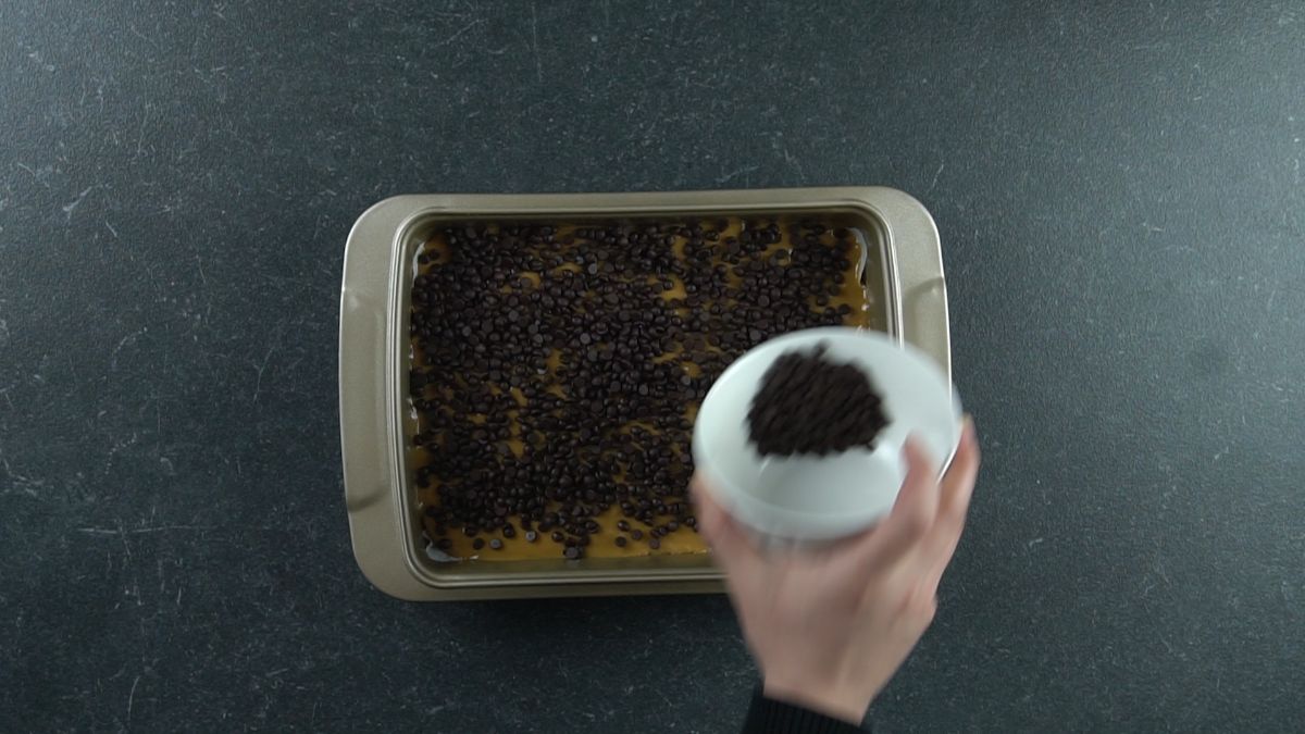 mini chocolate chips being poured over magic bars