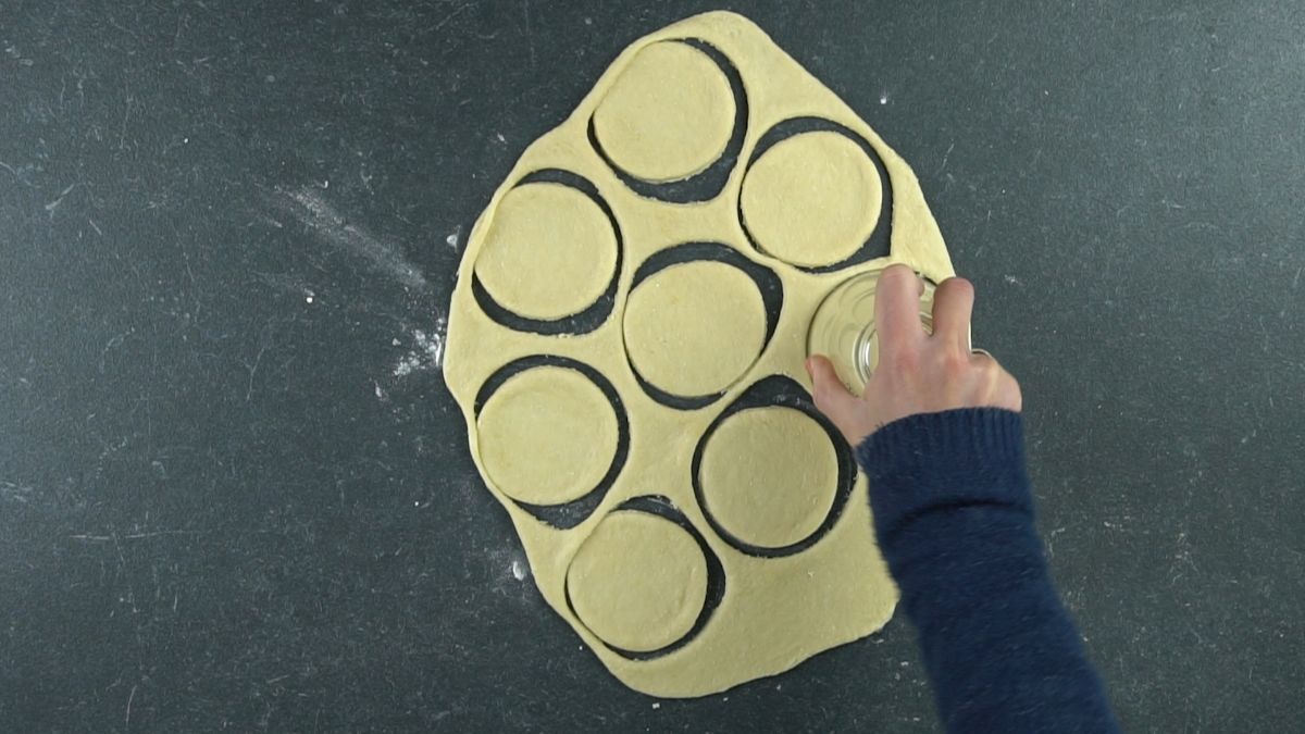 glass cutting out rounds of donut dough