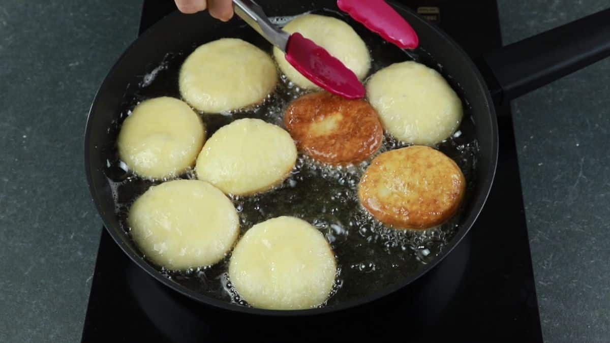 donuts being fried in skillet of oil