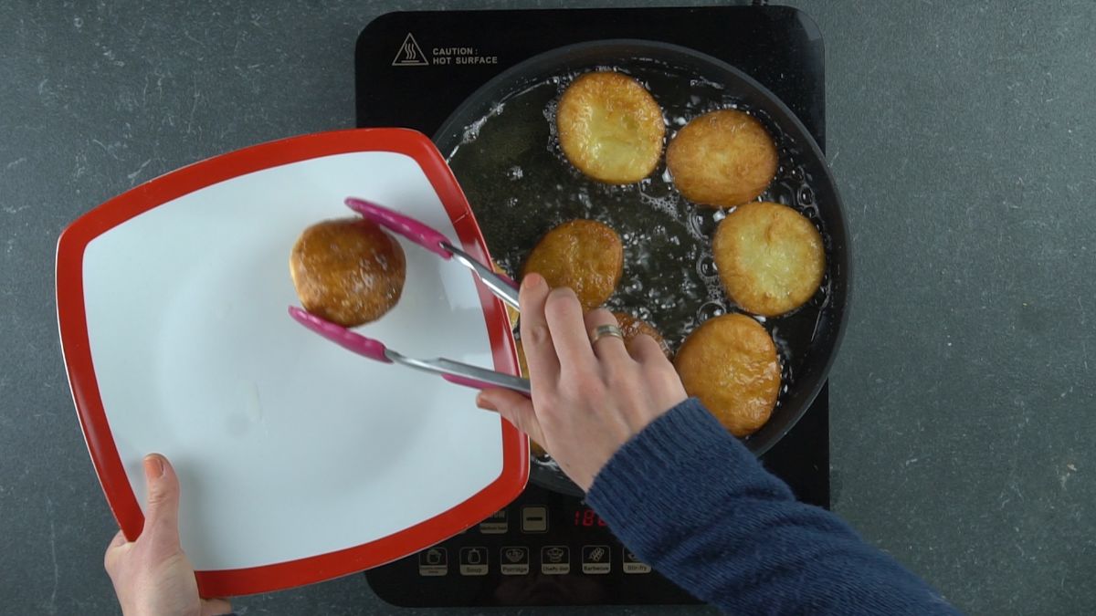 picking doughnuts out of skillet