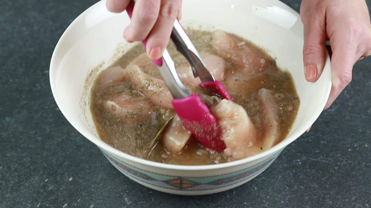 chicken breasts being dipped into brine