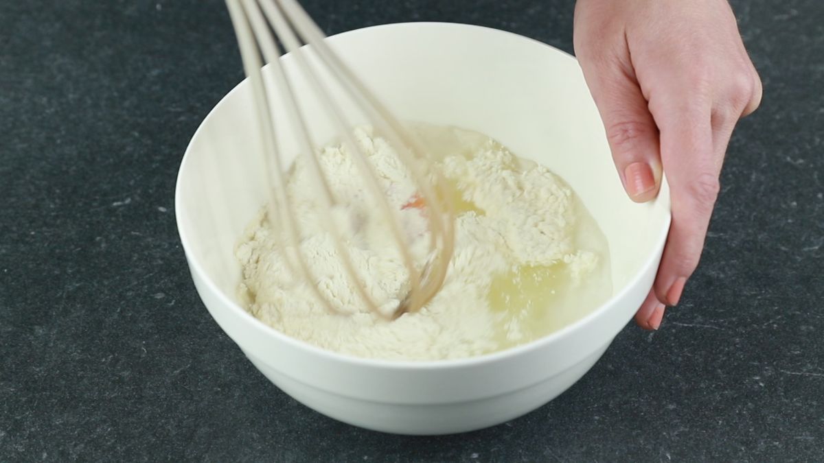 whisk stirring flour and egg in white bowl