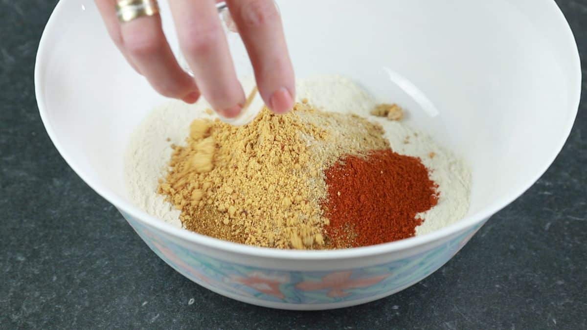 spices being added to white bowl