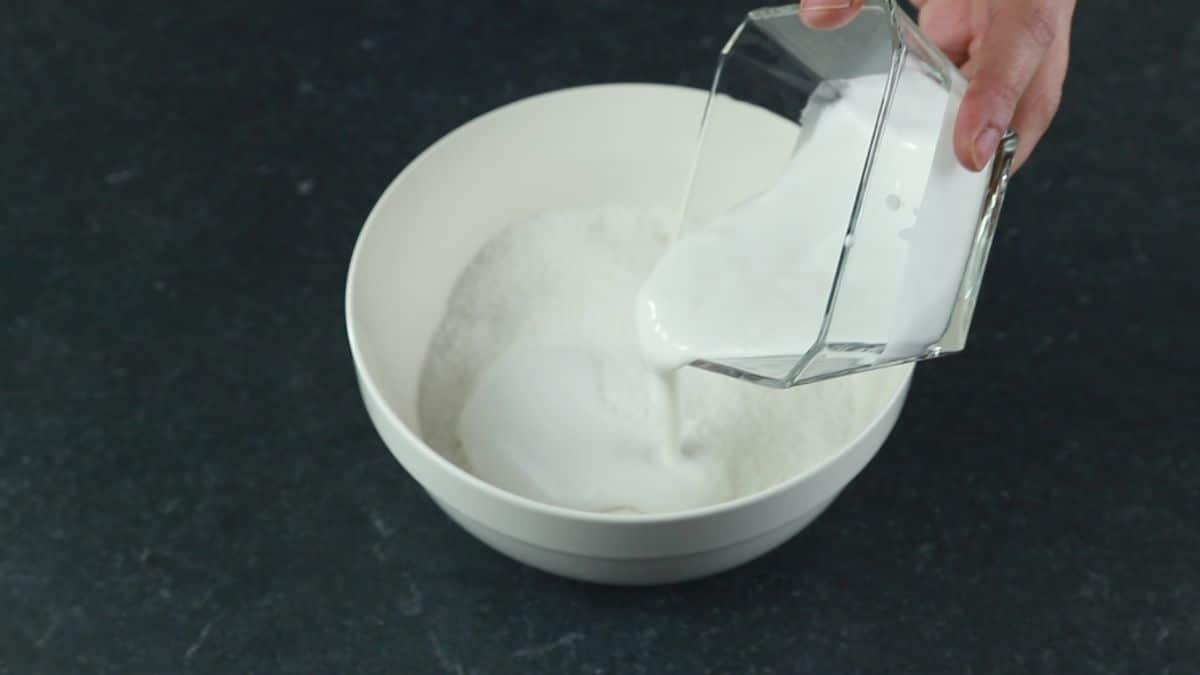 coconut milk being poured into bowl of coconut