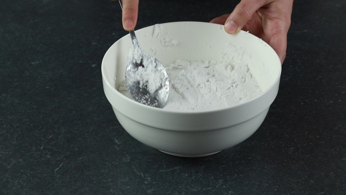 stirring coconut and coconut milk in white bowl