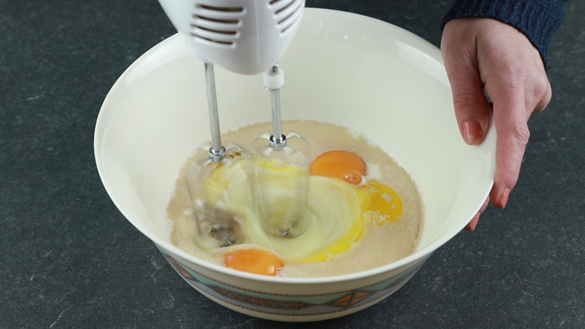 hand mixer in bowl with eggs and butter