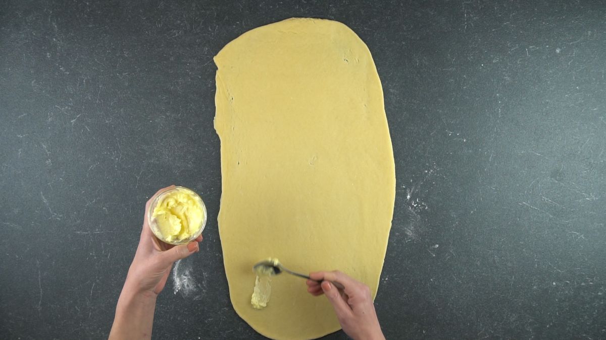 butter being spread onto dough