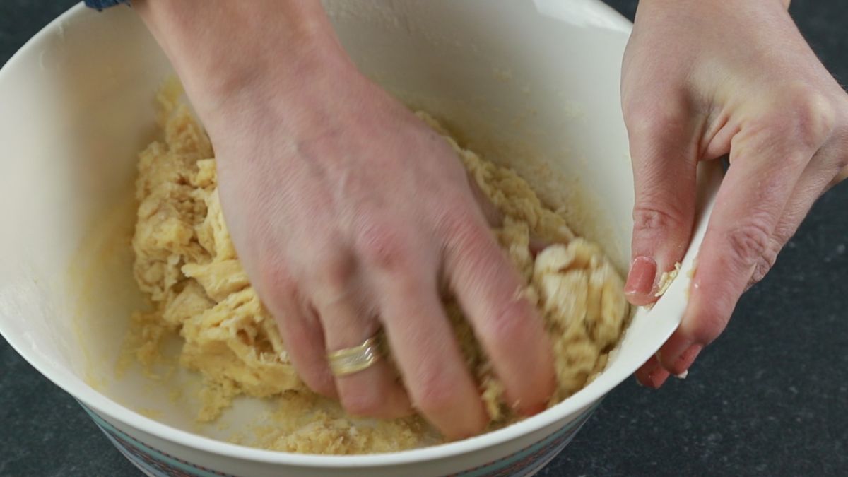hand kneading dough in white bowl