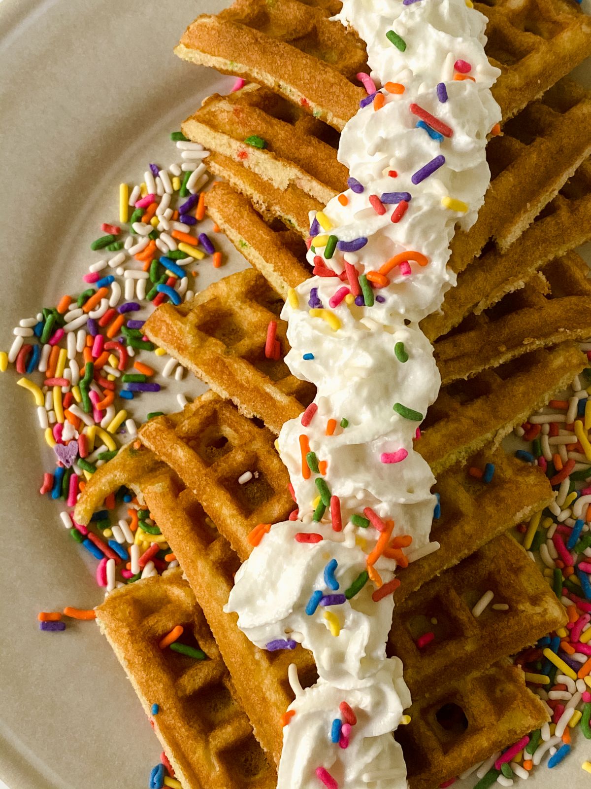 birthday cake waffles topped with whipped cream and sprinkles